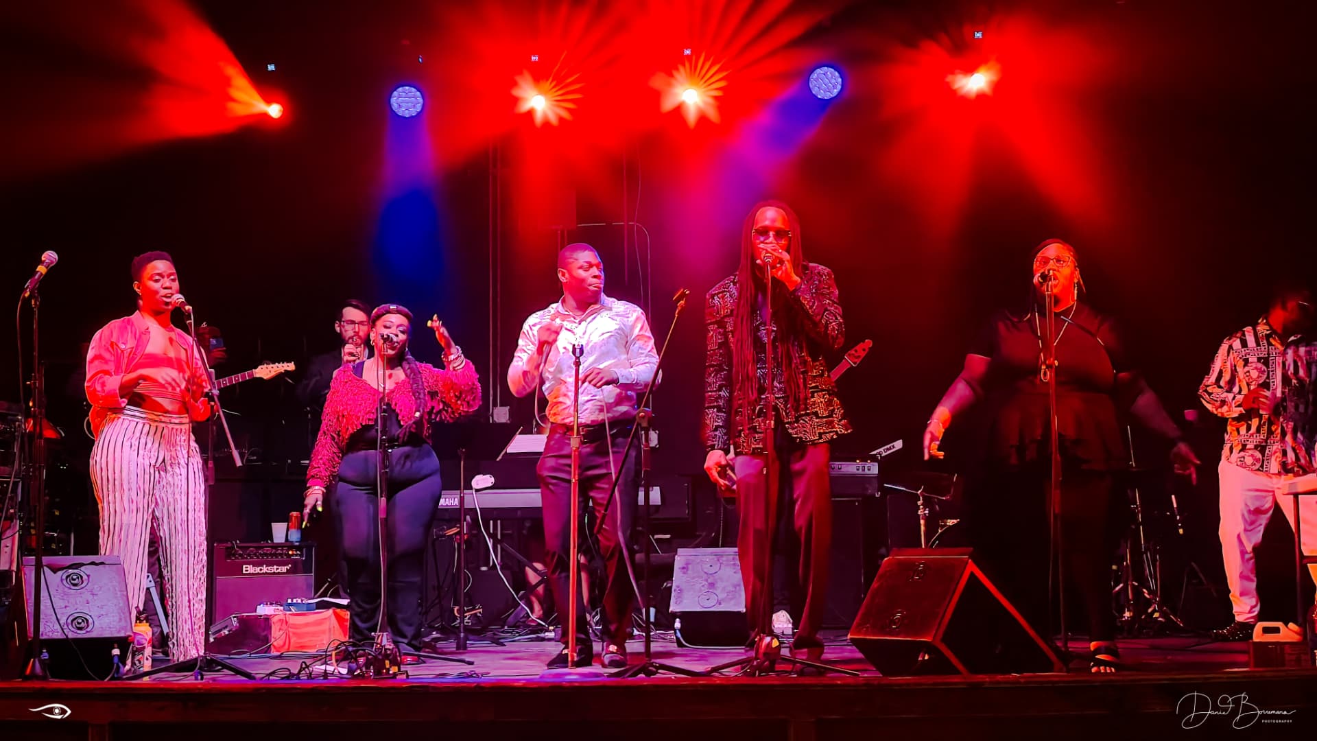 Live performers on stage under red concert lighting during a United GA Entertainment production.